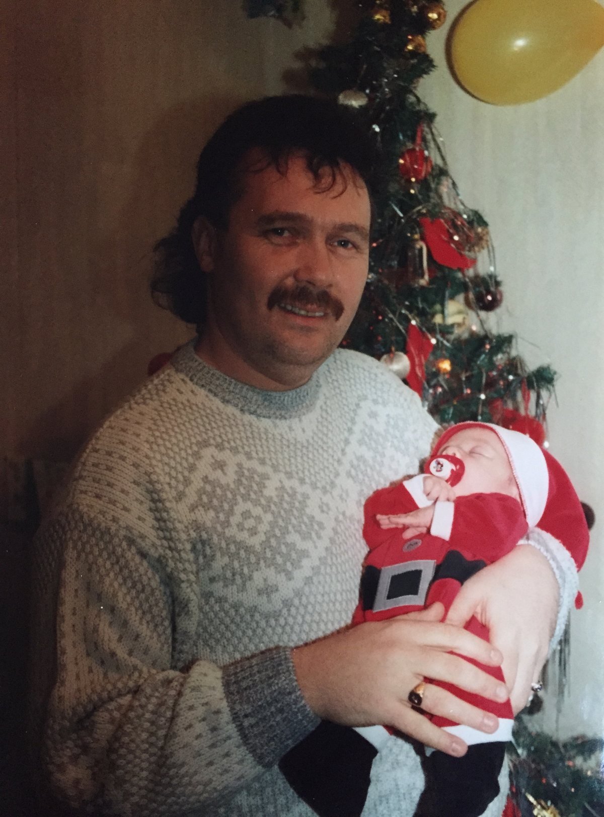 Terry holding baby Nick beside a Christmas tree