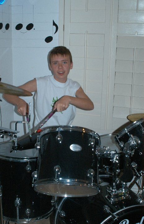 A young Nick behind a drum kit