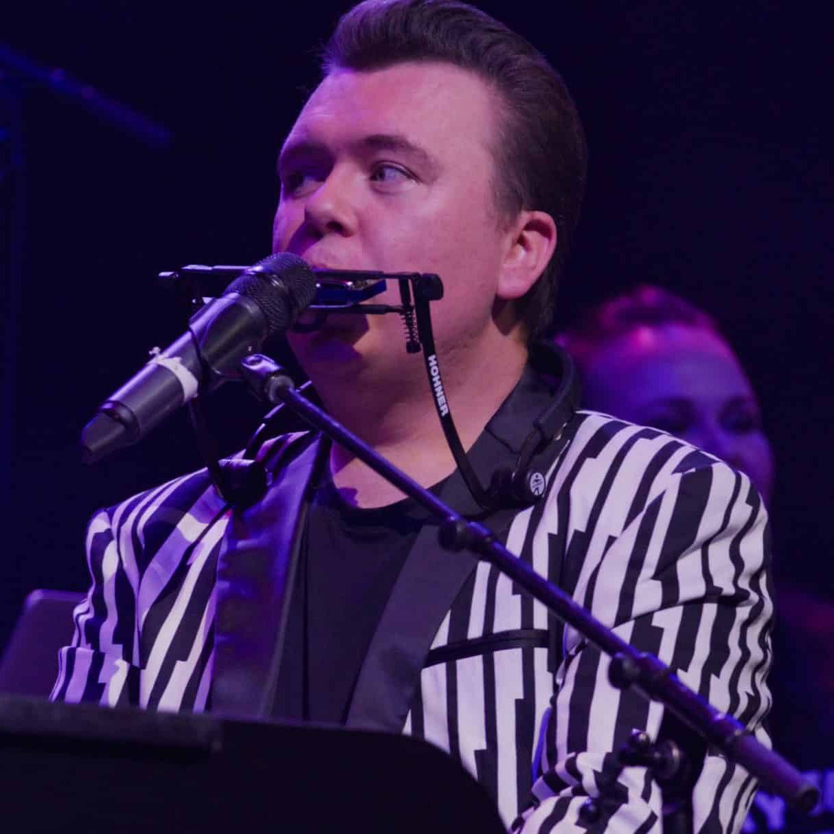 Nick Davies at the mic in a striped jacket